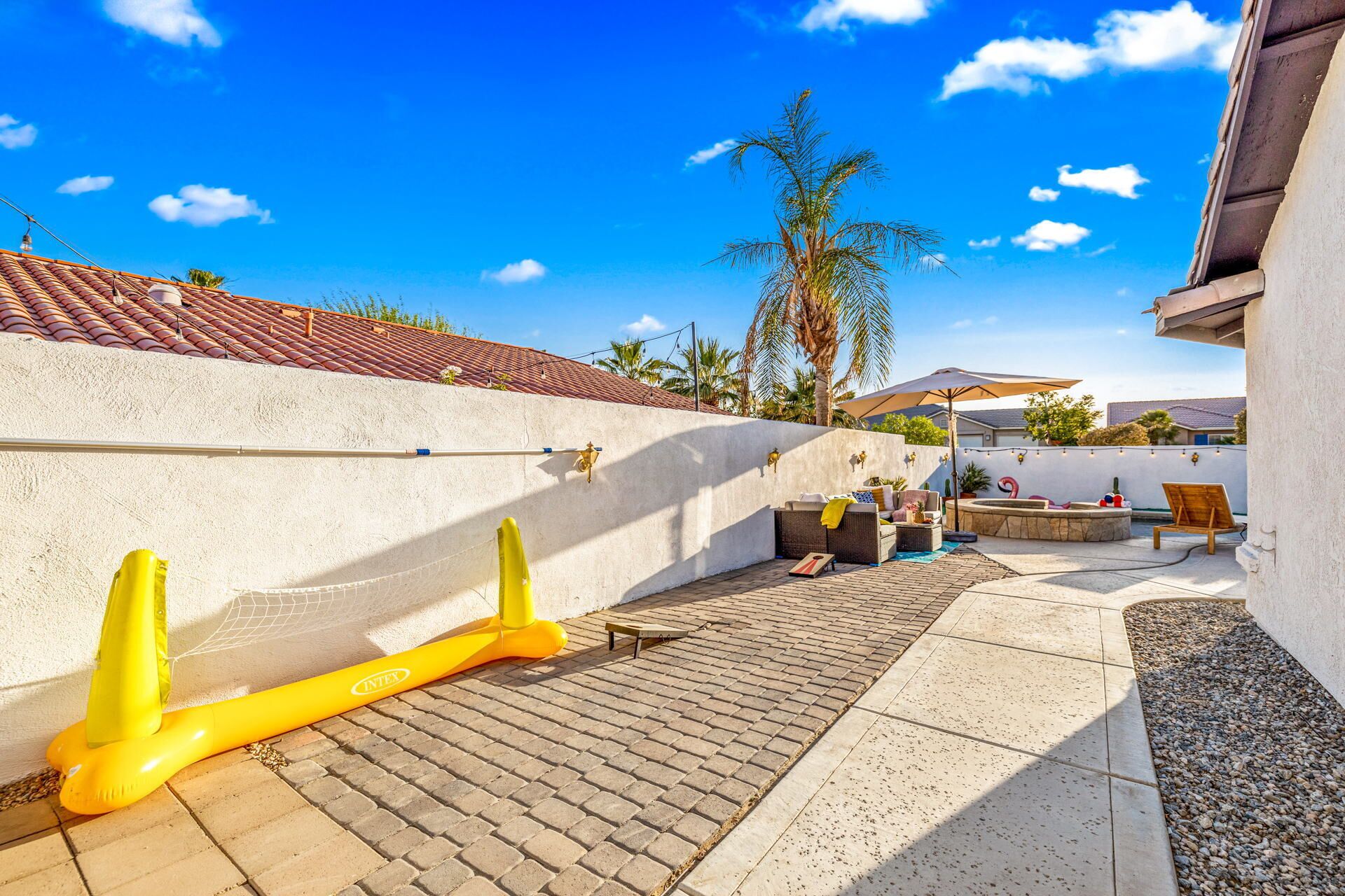 A patio with a white wall, tiled roof, and outdoor furniture including a sofa and a table.
