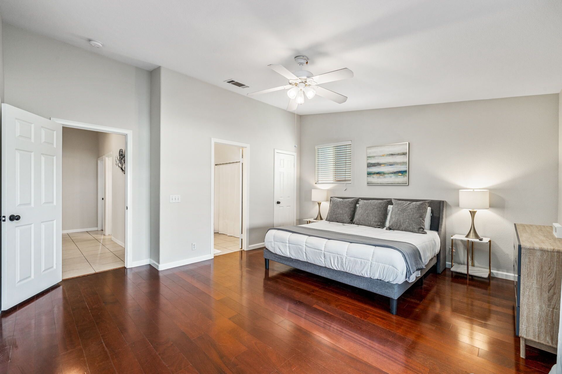 A spacious bedroom with a large bed, a ceiling fan, and a nightstand with a lamp.