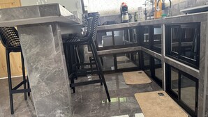 Una cocina moderna con encimera de mármol, taburetes negros y salpicadero de vidrio.