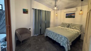 Un dormitorio con cama, una silla, una ventana con cortinas y un cuadro en la pared.