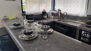 Una cocina moderna con encimera de mármol, cafetera, hervidor y pileta.