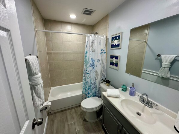 Un baño con bañera, inodoro, lavabo y cortina de ducha.