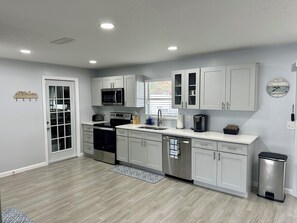 Una cocina moderna con armarios blancos, electrodomésticos de acero inoxidable y salpicadero de azulejos.