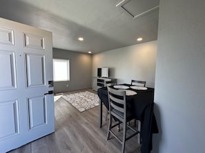 Cozy dining area with a table for four, cabinet, and TV.