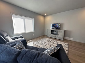 Relax in this stylish living room with a large sofa, flat-screen TV, and area rug.