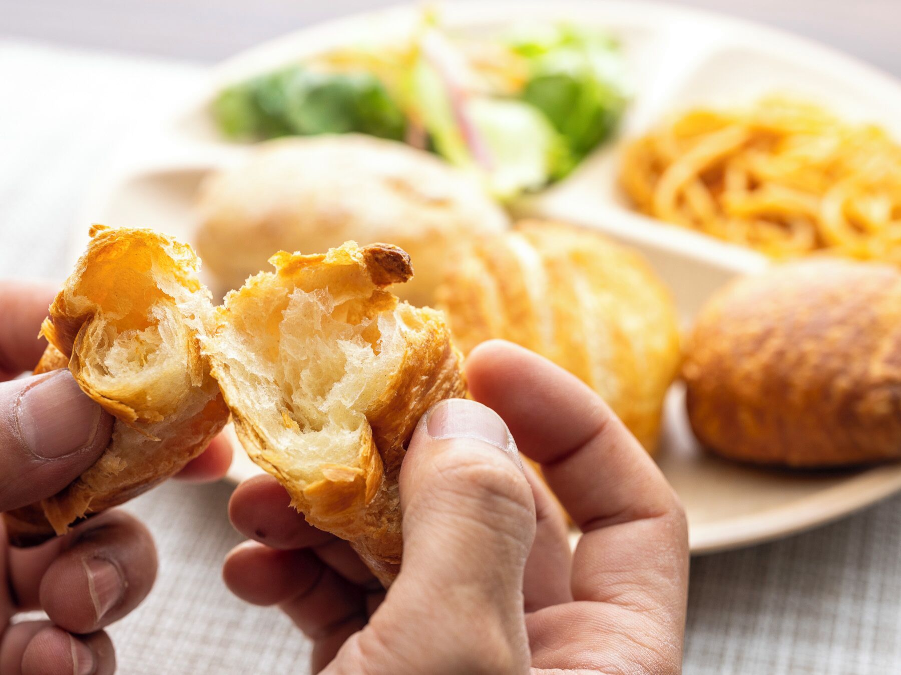A plate with a croissant and a salad.