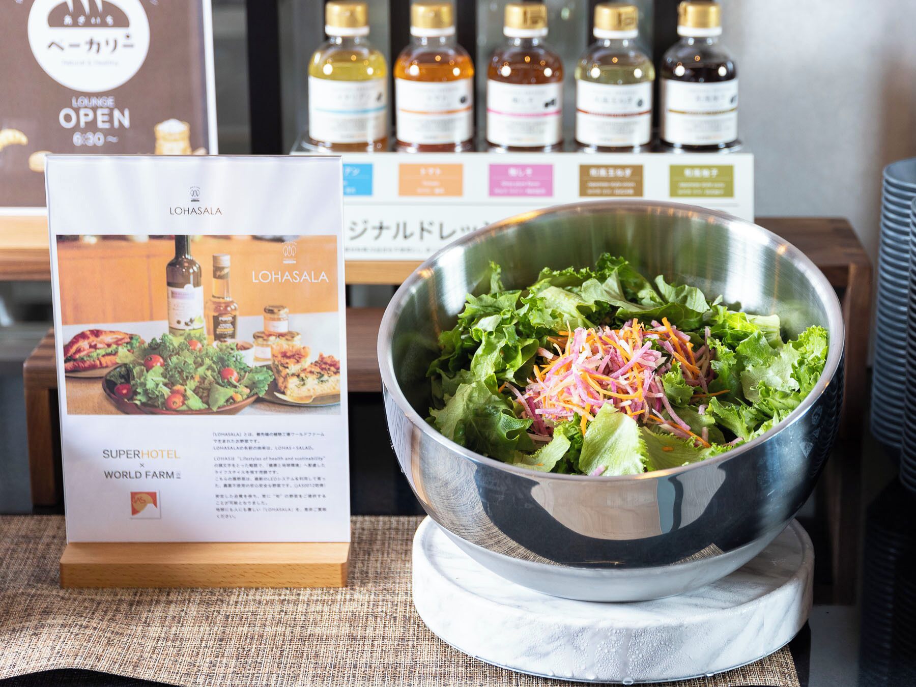 Un tazón de ensalada sobre una mesa con un cartel del menú de un restaurante y una fila de botellas al fondo.