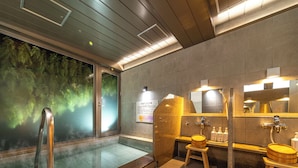Une salle de bain moderne avec une douche à parois de verre, un tabouret en bois et un lavabo avec un miroir.