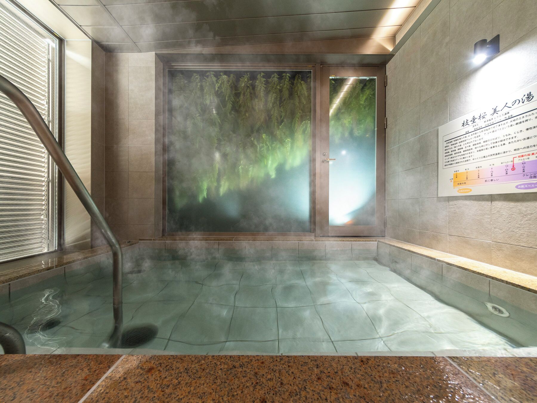 A steam room with a glass door, a steam pipe, and a sign on the wall.