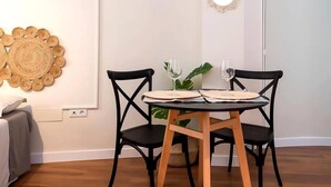 A dining area with a round table, two chairs, and a wall-mounted mirror.