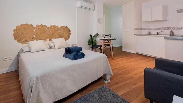 A bedroom with a bed, a bedside table, a chair, and a small table with a plant.