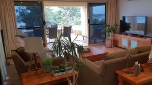 Un salón espacioso con televisor grande, asientos cómodos y vistas al exterior.