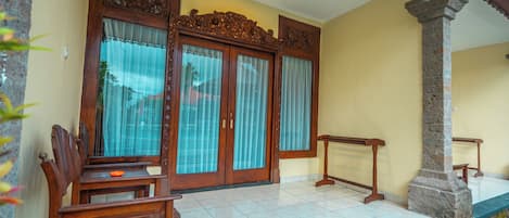 A room with a wooden bench, a stone pillar, and a door with intricate carvings.