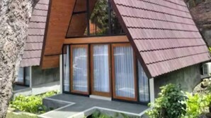 A modern house with a triangular roof, large windows, and a small garden. - The central lovina hotel & restaurant (Buleleng)