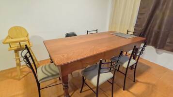 Uma área de refeições com uma mesa de madeira, quatro cadeiras e uma cadeira para bebê.
