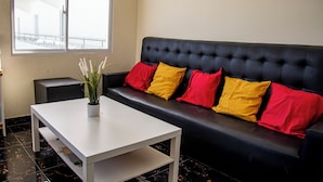 Ein modernes Zimmer mit einer schwarzen Ledersofa, einem weißen Couchtisch und einer Zimmerpflanze.