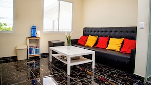 Ein modernes Wohnzimmer mit einer schwarzen Couch, einem weißen Couchtisch und einer kleinen Pflanze.