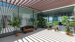 Un espacio exterior moderno con paredes de vidrio, listones de madera y plantas en macetas.