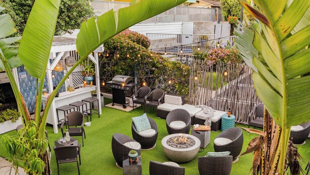 Un patio al aire libre con mobiliario de mimbre, un brasero y luces colgantes.