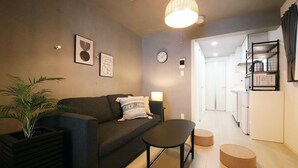 Een moderne woonkamer met een bank, een salontafel en een eethoek, met een keuken op de achtergrond.