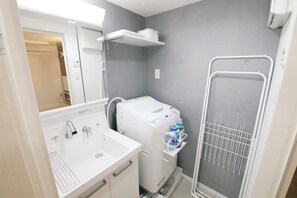 A compact bathroom with a sink, a white washing machine, and a shower enclosure. - Stellar Nishikoujiya 201  (Tokyo)