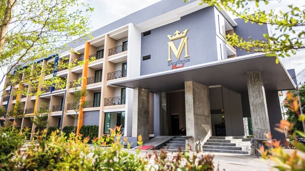 A multi-story hotel with a prominent 'Boutique' sign and a crown logo. - M Boutique Resort (Chiang Rai)
