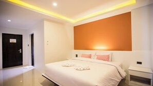 A modern hotel room with a large bed, a bedside table, and a wall-mounted light fixture. - M Boutique Resort (Chiang Rai)