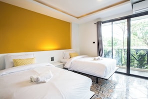 A hotel room with two beds, a yellow accent wall, and a balcony with a view. - M Boutique Resort (Chiang Rai)