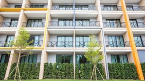 A multi-story hotel with balconies, large windows, and a well-maintained hedge in front. - M Boutique Resort (Chiang Rai)