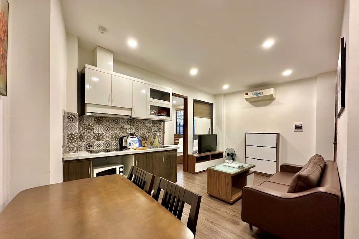 A compact living space with a dining area, kitchenette, and a seating area with a sofa and a TV.