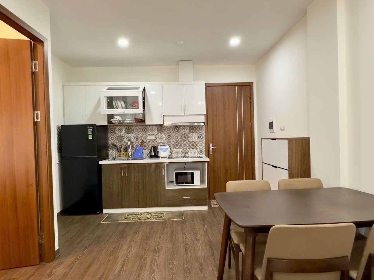 Eine kompakte Küche mit Kühlschrank, Mikrowelle und einer Essecke mit Tisch und Stühlen.