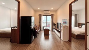 Habitación de hotel con cama, escritorio, refrigerador, televisor y dispensador de agua.