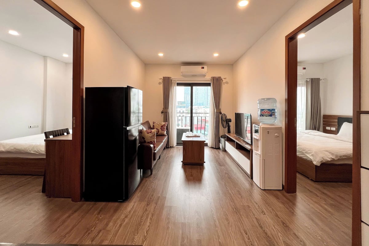 A hotel room with a bed, a desk, a refrigerator, a TV, and a water dispenser.