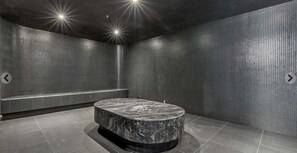 A modern bathroom with a marble sink, tiled walls, and a bench.