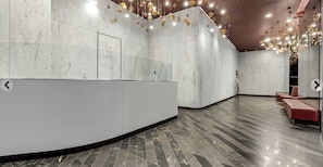 A modern reception area with a curved counter, marble walls, and a polished floor.