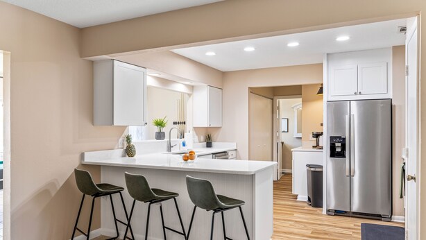 A modern kitchen with a central island, bar stools, stainless steel appliances, and a minimalist design.