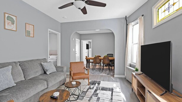 Un salon moderne avec un canapé gris, une table basse, un meuble pour la télévision et un coin repas comprenant des chaises et une table.
