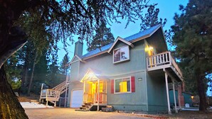 A two-story cabin with a porch, a chimney, and a mailbox.