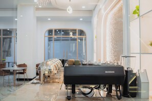 A modern coffee station with a branded espresso machine, seating area, and a large window providing natural light.