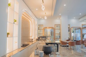A modern hotel lobby with a marble floor, a coffee station, and a seating area with chairs.