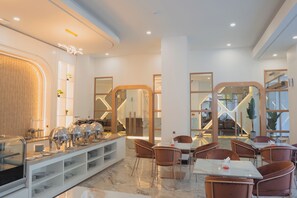 A modern hotel dining area with a buffet, seating, and a view of the interior.