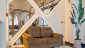 A modern lobby with a unique geometric wall design, a comfortable sofa, and a large potted plant. - Fahira Hotel Syariah Padang (Padang)