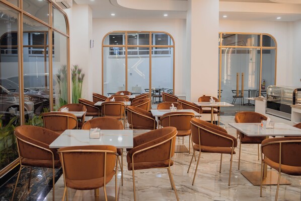 A modern restaurant interior with marble flooring, brown upholstered chairs, and large windows offering views of the street.