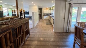 A kitchen with a wooden floor, white cabinets, and a large mirror.