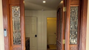 A wooden double door with glass panels and a doormat at the entrance.