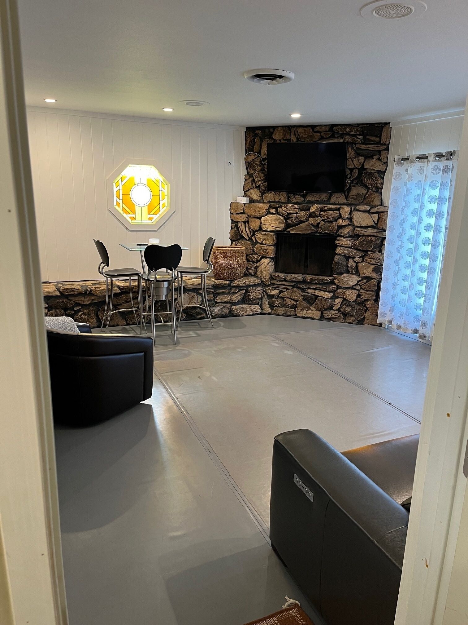 Un salon avec une cheminée en pierre, un coin repas avec des chaises et un canapé.