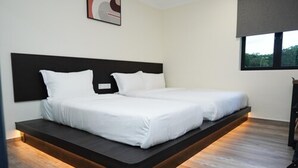 A modern bedroom with a bed that extends to the floor, a dark headboard, and a window with a view of greenery. - Anta Hotel  (Johor Bahru)