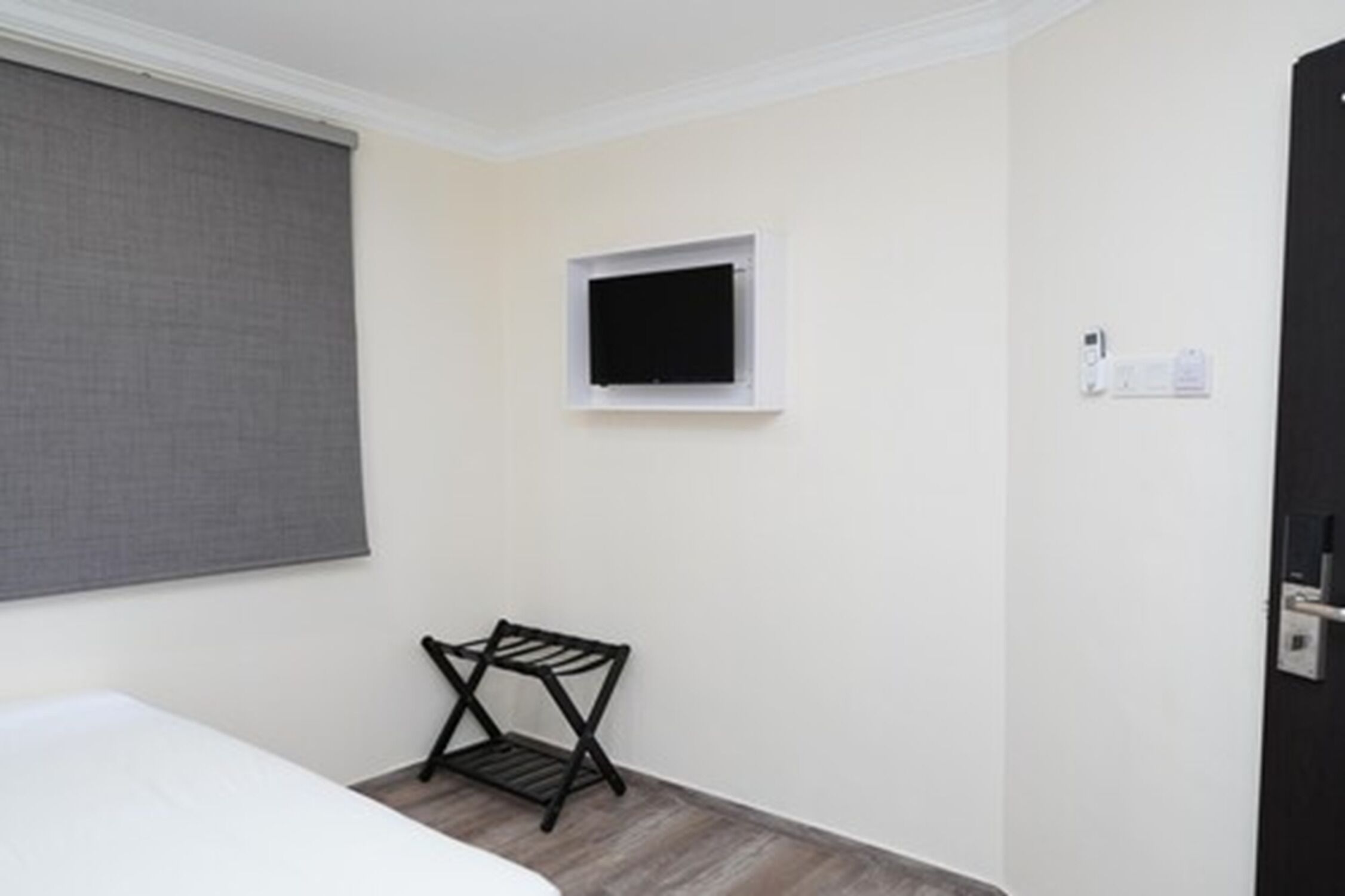 A small, simple room with a bed, a window, a small table, and a door.