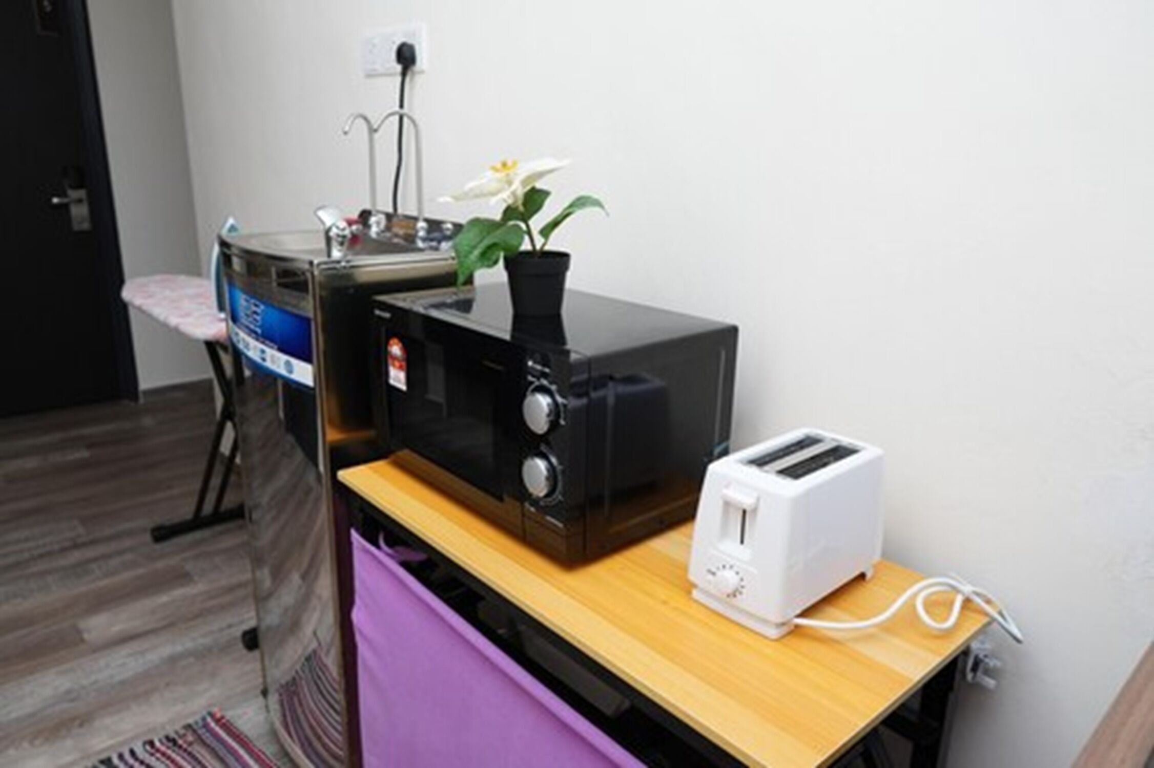 Une petite cuisine équipée d’un four à micro-ondes, d’un grille-pain et d’une petite plante en pot.