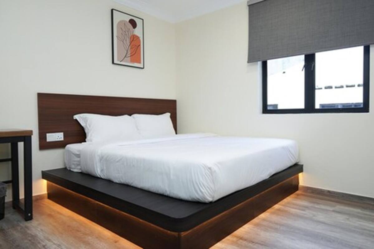 A modern bedroom with a bed, a nightstand, and a window.